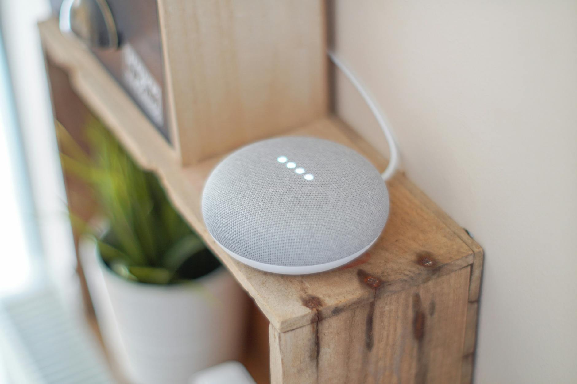 Głośnik Google Home Mini na drewnianej półce w nowoczesnym salonie