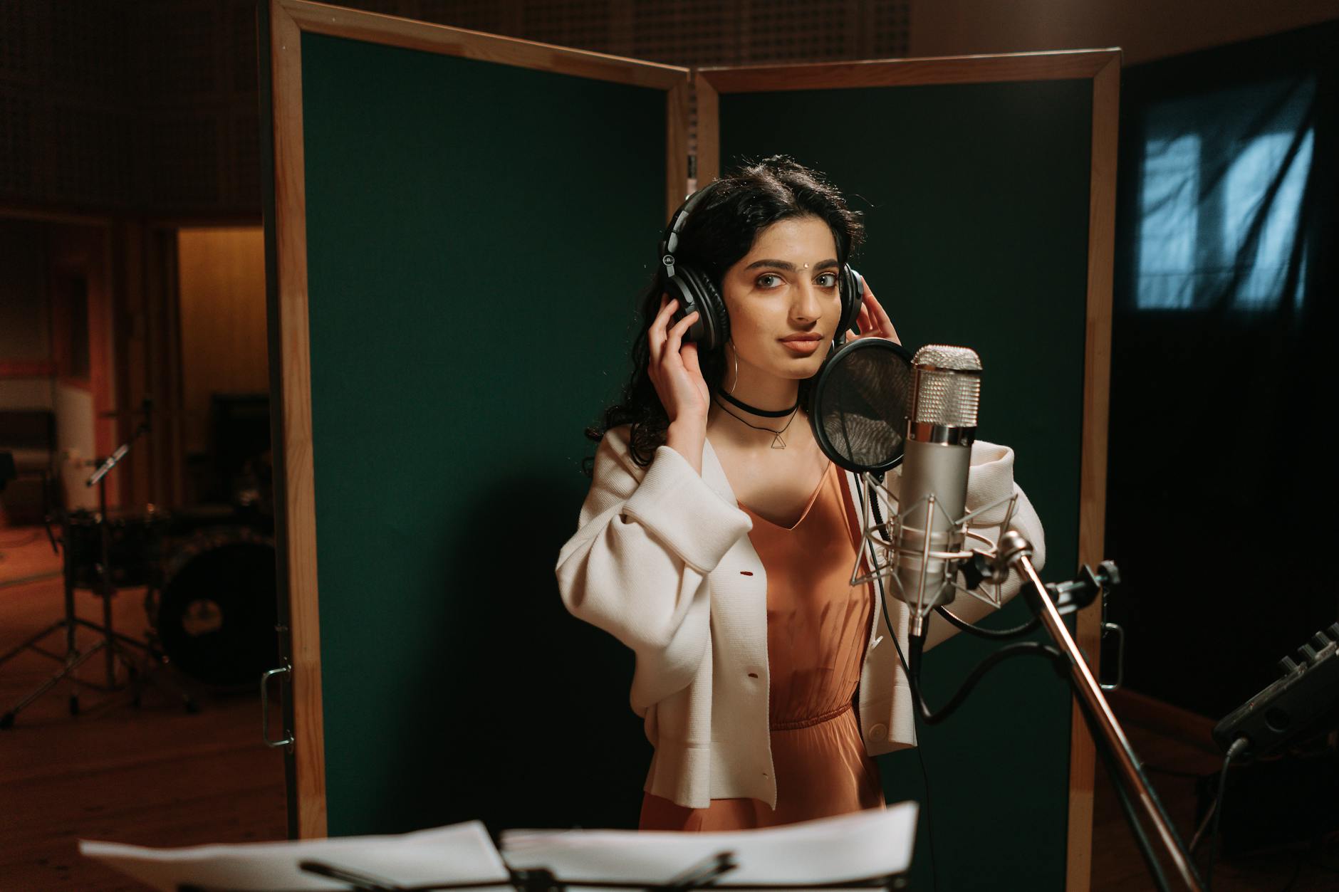 Kobieta nagrywająca wokal w profesjonalnie wyciszonym studiu muzycznym
