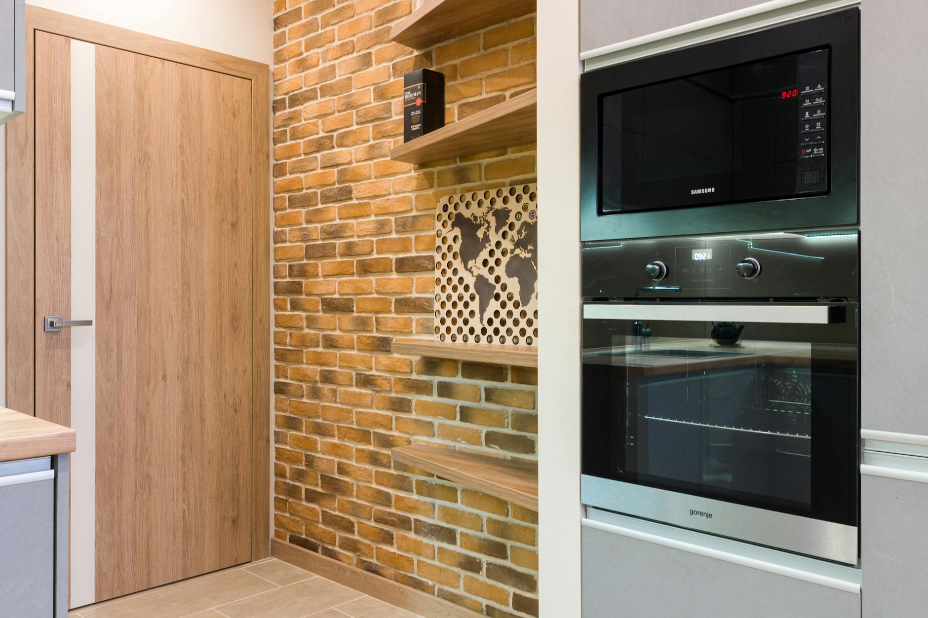 Wąska kuchnia w bloku z ceglaną ścianą i nowoczesnym AGD