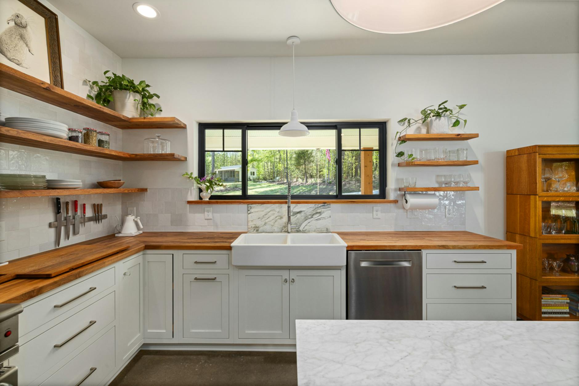 Jasna kuchnia z otwartymi półkami, zlewem farmerskim i drewnianym blatem