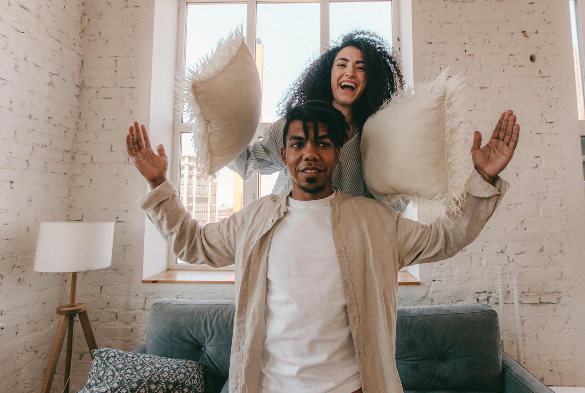 Para w salonie w trakcie radosnej bitwy na poduszki