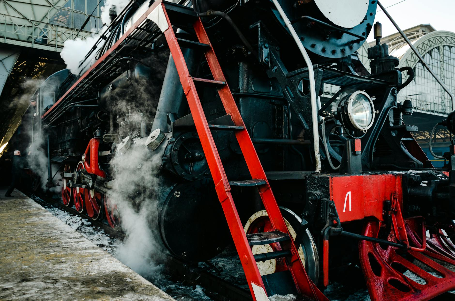 Zabytkowa lokomotywa parowa na tle zimowego dworca kolejowego