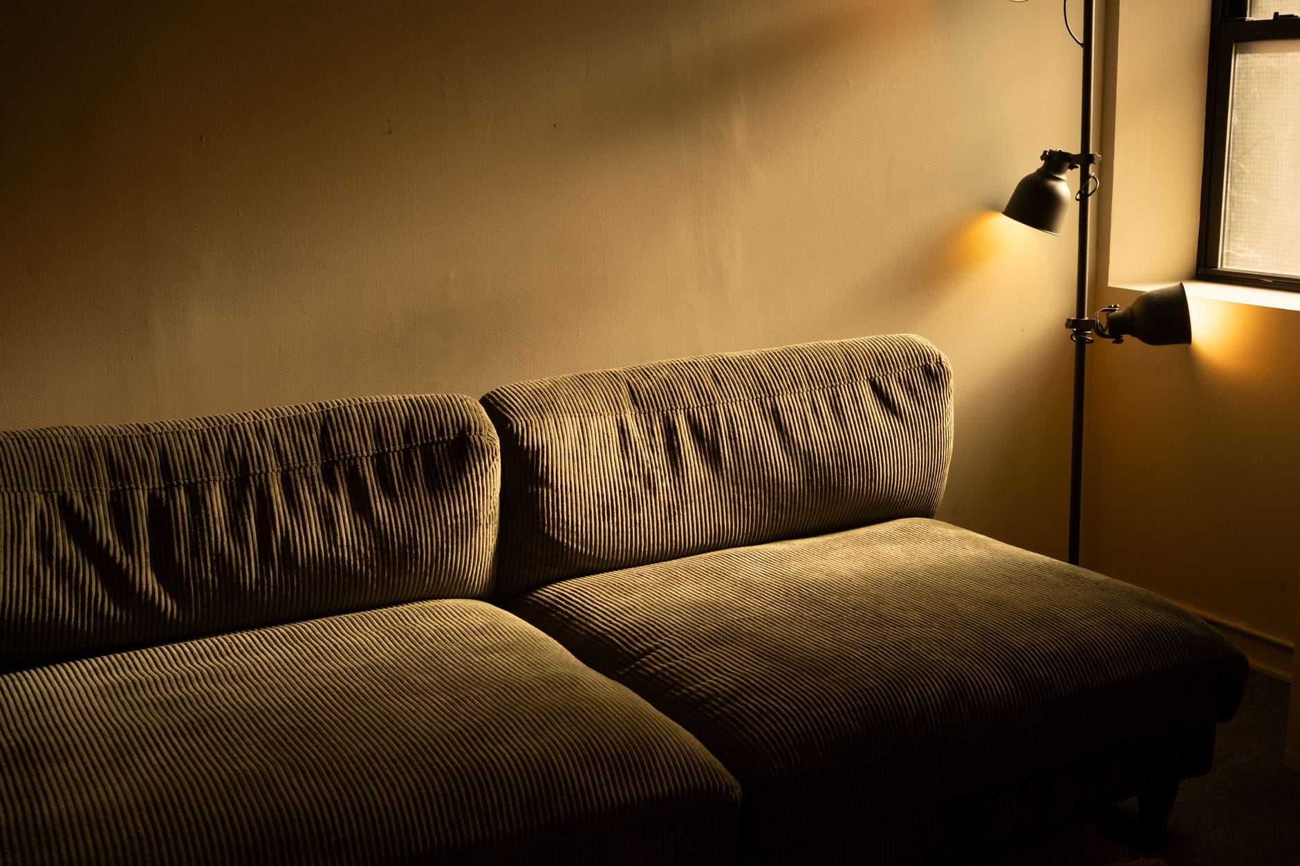Przytulny salon w bloku z szarą kanapą w ciepłym, przyciemnionym świetle